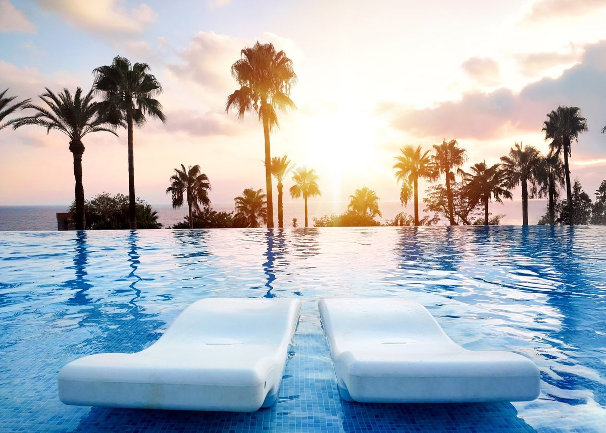 A tranquil sunset view over an infinity pool with palm trees in Bali