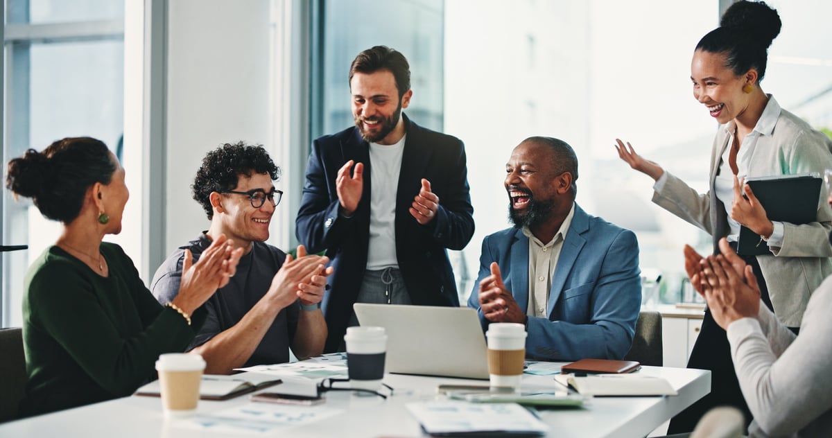 Business people celebrating achievement at an office meeting, representing sales success and revenue growth