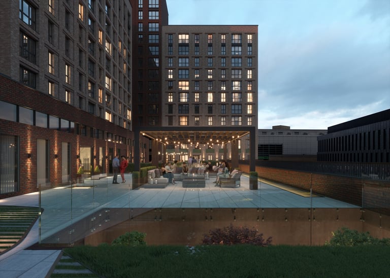 Evening view of a modern urban courtyard with illuminated buildings, outdoor seating, and a reflective water feature at dusk