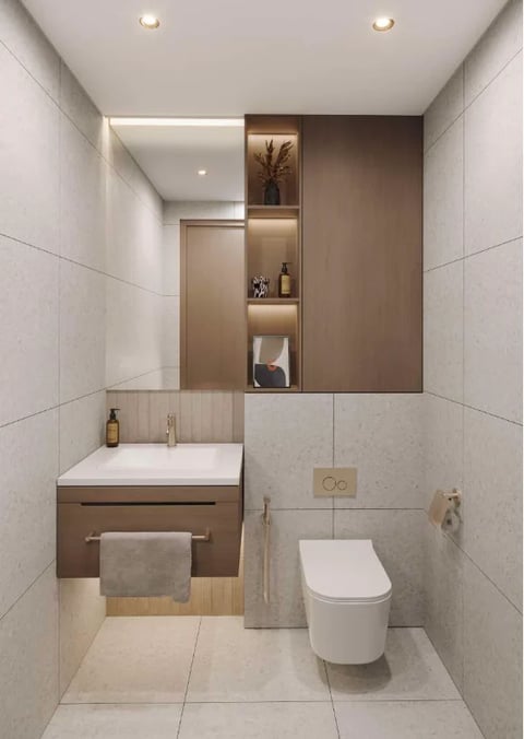 Modern small bathroom with white ceramic tiles, brown vanity, wall-mounted toilet, recessed shelving with decorative items, and warm lighting